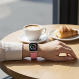Bakers Bands Limited bright guava nylon woven sport loop band on an Apple Watch worn at a cafe table with coffee.
